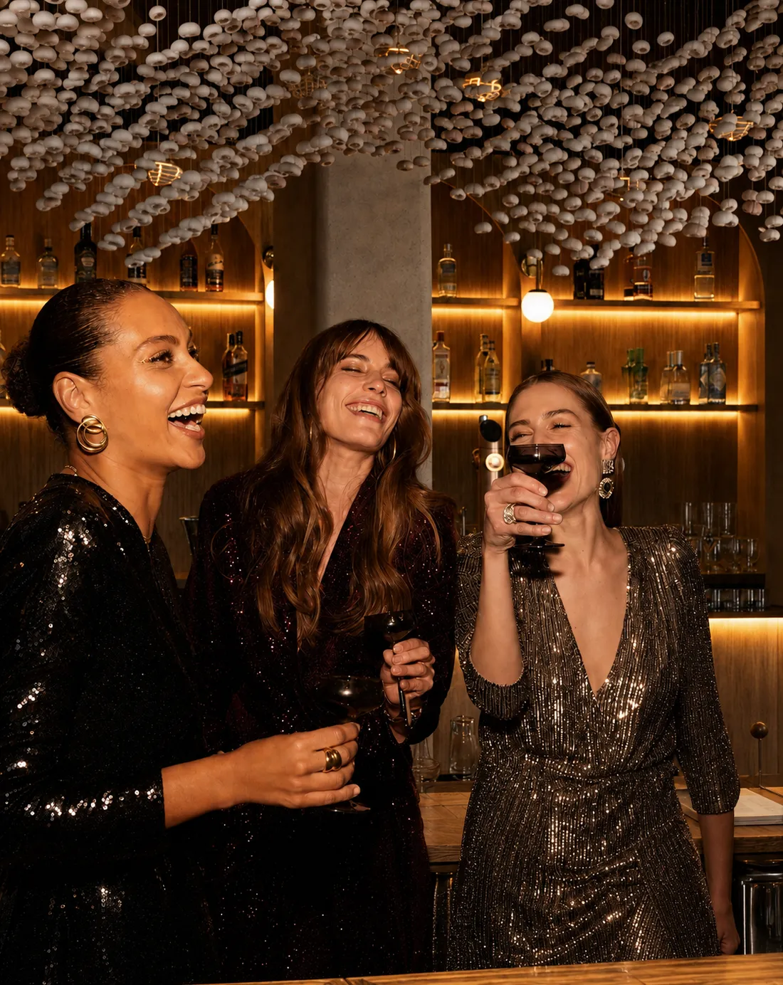 Tres clientas riendo con sus copas en la barra del restaurante